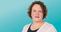 Frau mit kurzen lockigen Haaren vor blauem Hintergrund