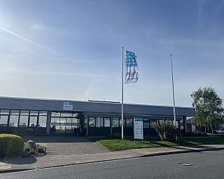 Gebäude mit großen Fenstern und einer wehenden Firmenflagge bei klarem Himmel