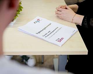 Personen im Gespräch mit einem Dokument zum Ergänzungskonzept auf einem Tisch