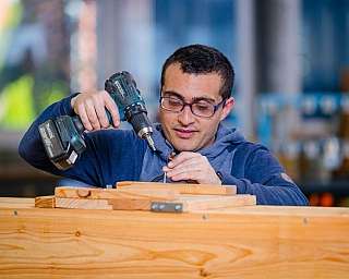 Ein Mann arbeitet mit einem Akkuschrauber an einem Holzprojekt.