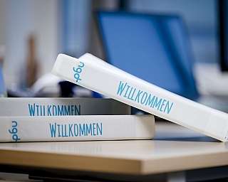 Weiße Ordner mit dem Wort Willkommen im Büro auf einem Tisch
