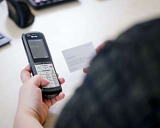 Person hält IP-Telefon und weiße Karte zur Wahlvorbereitung