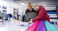 Zwei Personen im Büro, die bunte Folienmaterialien bearbeiten