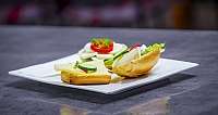 Sesambrötchen mit Frischkäse, Tomate, Gurke und Salat auf weißem Teller