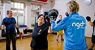 Menschen mit Boxhandschuhen trainieren in einer hellen Sporthalle mit Boxhandschuhen