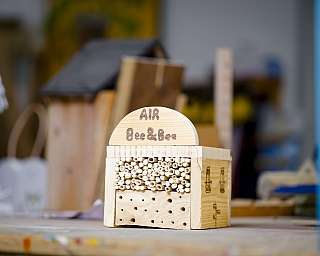 Nahaufnahme eines aus Holz gefertigten Insektenhotels mit hohlen Stängeln und Löchern