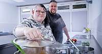 Zwei Personen in einer modernen Küche kochen gemeinsam und schauen in einen Topf