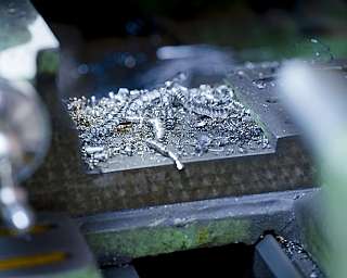Nahaufnahme von silbernen Metallspänen auf grünem Maschinenbett in Werkstatt