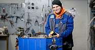 Mechaniker mit Mütze und Jacke hält Filter in einer Werkstatt